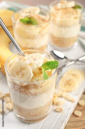 Glass with delicious banana pudding on wooden board