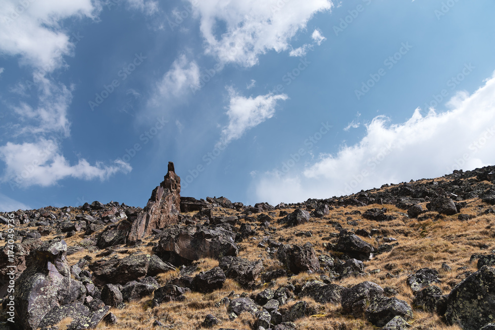 High-mountainous sharp rocks against the blue sky and white clouds. Caucasus