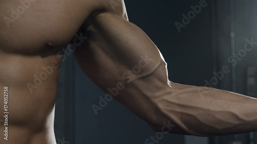 A fitness model tenses up his bicep muscle displaying its form. Close up. photo