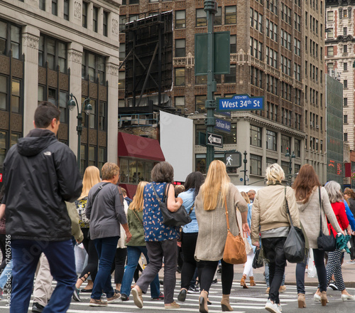 People walk across a busy Manhattan crosswalk in New York City during rush hour evening commute travel to work and home