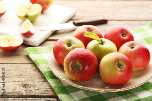 Ripe and sweet apples in plate on grey wooden table