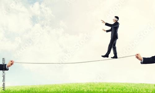 Business concept of risk support and assistance with man balancing on rope