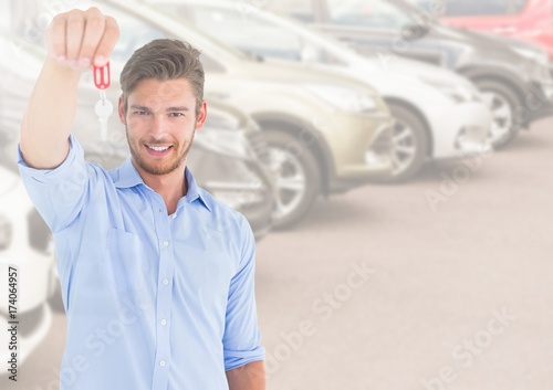 Man Holding key in front of cars
