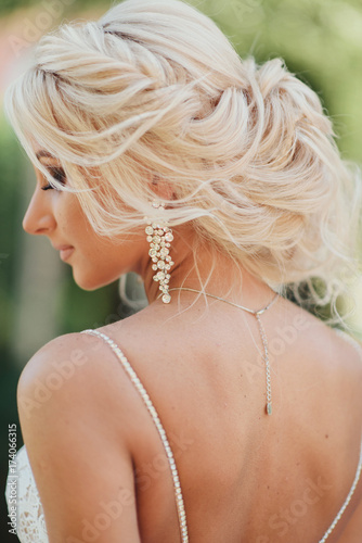 Gentle portrait of the bride in a white dress, the rear view. A hairstyle on a wedding, the beautiful blonde