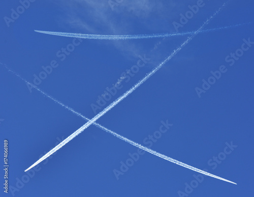 A jet plane flying overhead diagonally with condensation trail.
