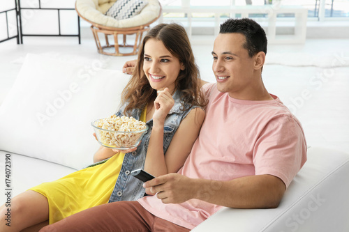 Young couple watching TV at...