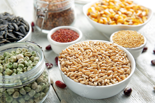 Different grains in kitchenware on light background