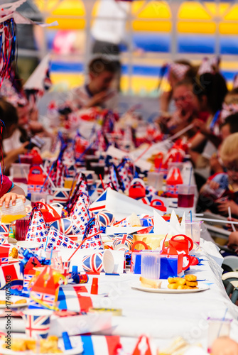 Billede på lærred Children sit at long tables with red, white and blue party accessories at a Roya