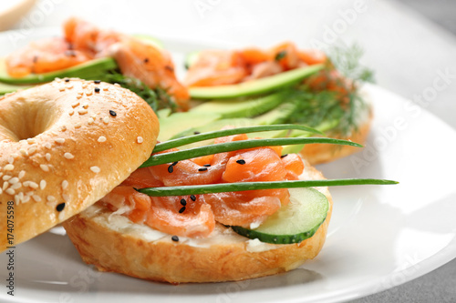 Delicious salmon bagel on plate, closeup