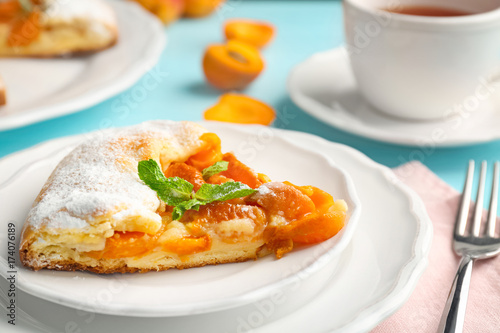 Plate with piece of delicious apricot cake on table