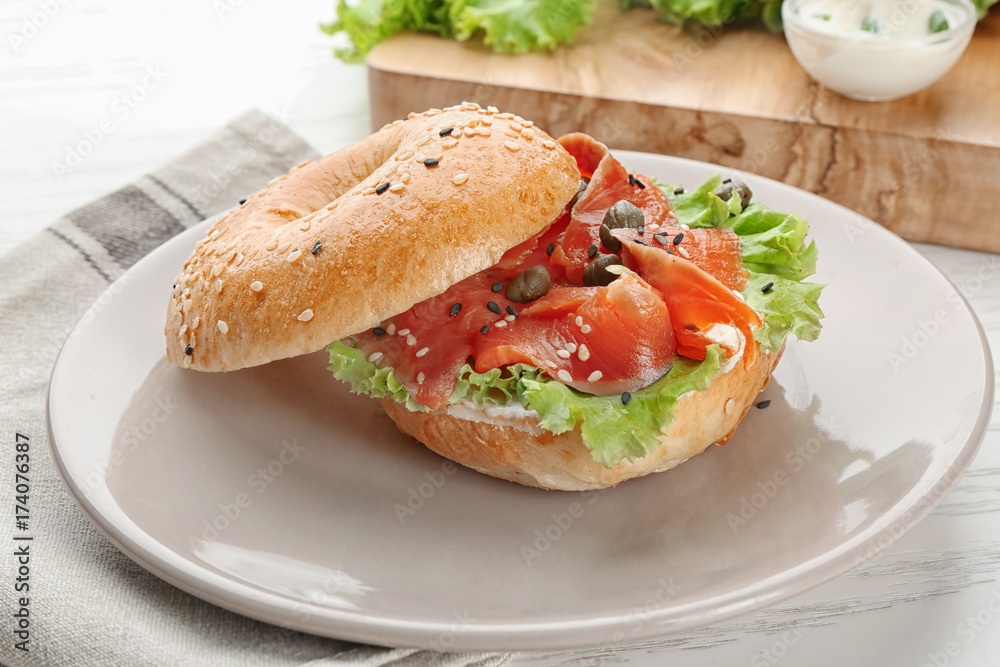 Tasty bagel sandwich with salmon and vegetables on plate Tasty bagel sandwich with salmon and vegetables on plate