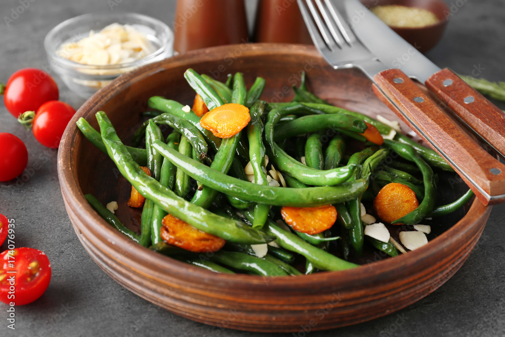Bowl with delicious green beans, almond and carrot slices on table