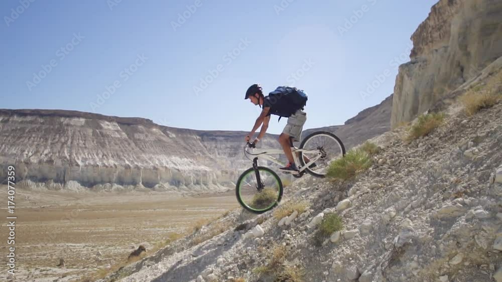 A young man on a bicycle is rolling from the mountain. Slow motion A young man on a bicycle is rolling from the mountain. Slow motion