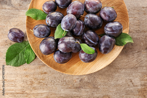 Fresh ripe plums on wooden plate