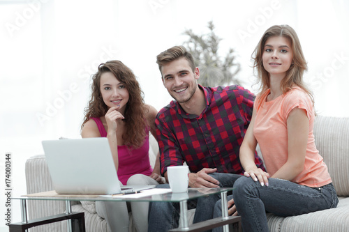 group of students sitting on a couch behind a coffee table.