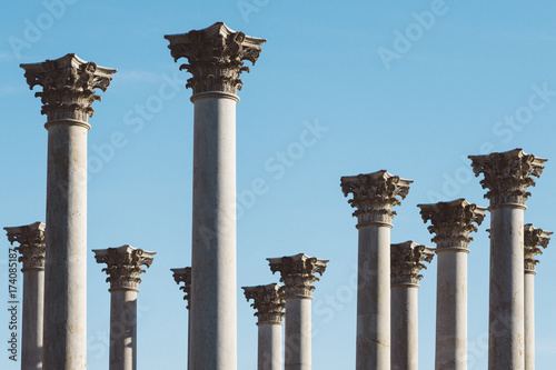 A grouping of corinthian columns against a clear blue sky.