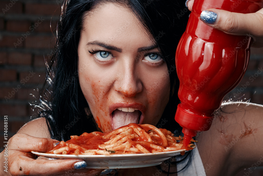 Sexy seductive cheeky girl in a white T-shirt and a plate of pasta with  ketchup,