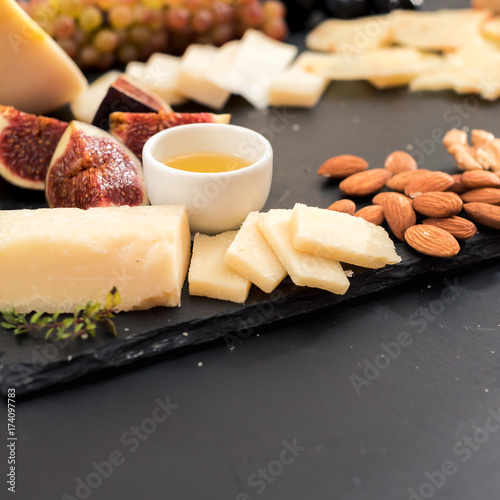 honey sliced parmesan cheese nutse fruit black background photo