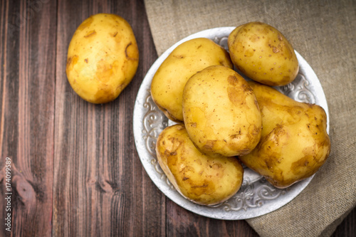 Raw potatoes on a brown wooden background