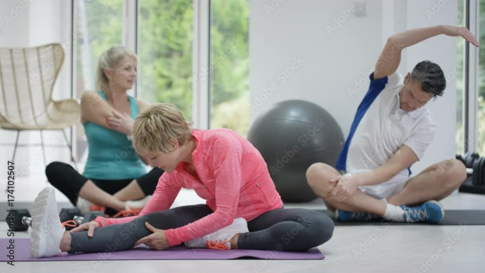 Mature female fitness instructor working out with 2 clients in exercise class Mature female fitness instructor working out with 2 clients in exercise class