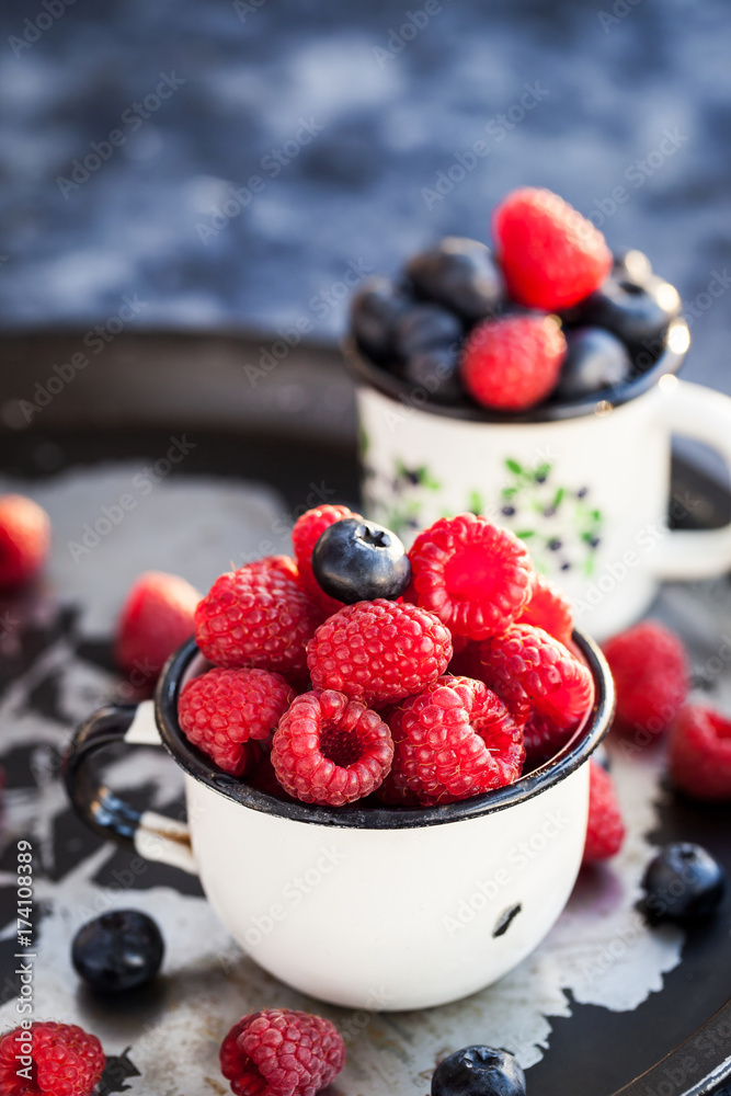 Fresh ripe blueberry and raspberry in mugs Fresh ripe blueberry and raspberry in mugs