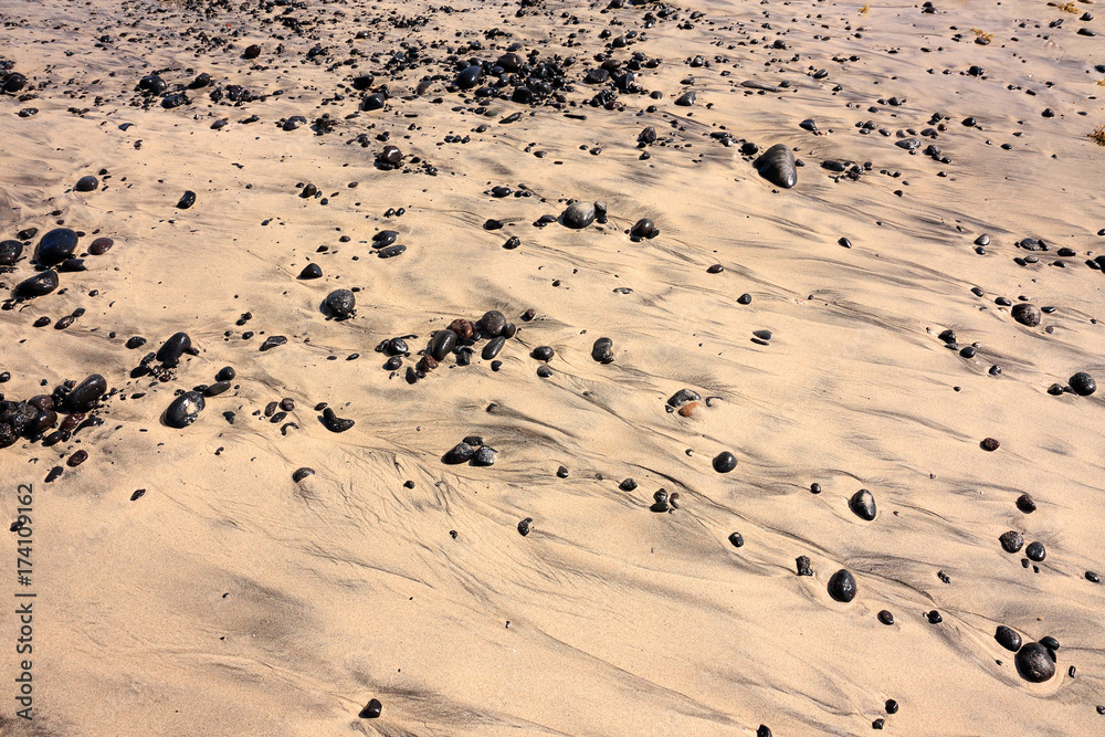Black stones on a sandy beach Black stones on a sandy beach