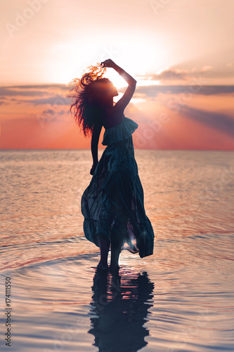Fototapeta Elegant woman on water. Sunset and silhouette