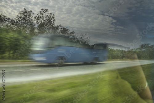 Bus racing past, paggenger asleep, White Clouds, Trees and Green Grass