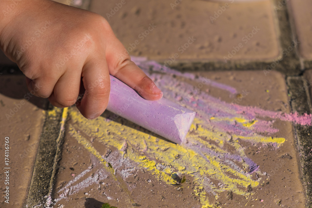 Child drawing with large color chalk on the floor outdoors Child drawing with large color chalk on the floor outdoors