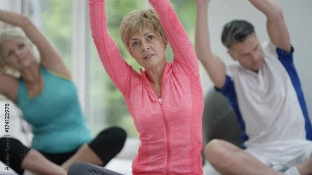 Mature female fitness instructor working out with 2 clients in exercise class Mature female fitness instructor working out with 2 clients in exercise class