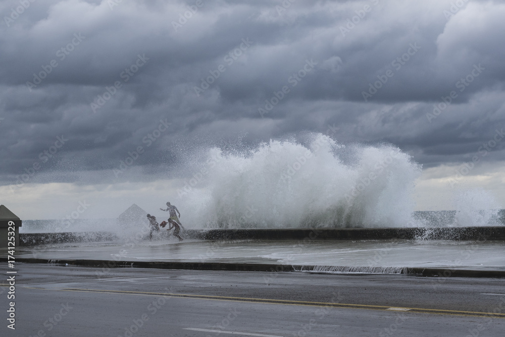 Large Waves on the Malecon, Old Havana, Cuba, with 3 people running for safety.