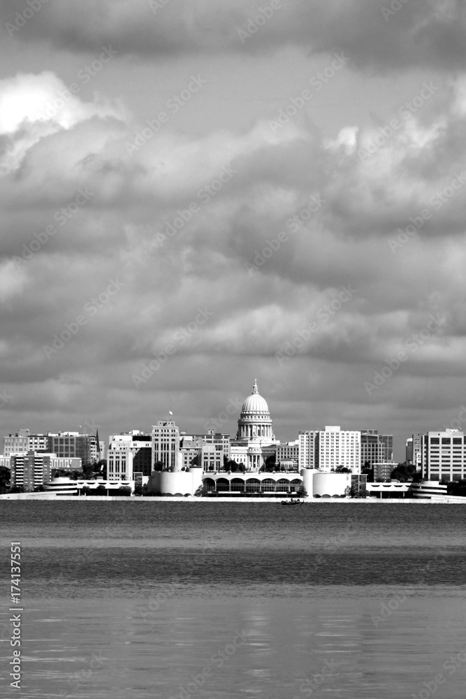 Downtown skyline of Madison, the capital city of Wisconsin, USA. Morning view with State Capitol and official buildings in sunlight against beautiful cloudy sky in black and white.