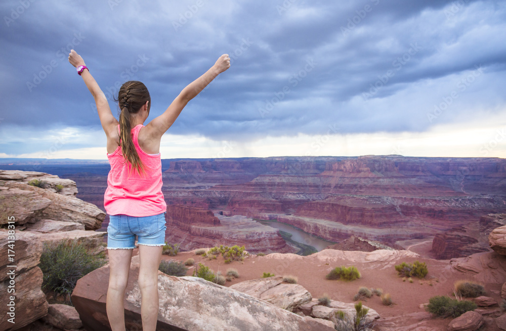 Young woman viewing the beautiful scenic overlook of Dead Horse Point. She is raising her hands in amazement Young woman viewing the beautiful scenic overlook of Dead Horse Point. She is raising her hands in amazement