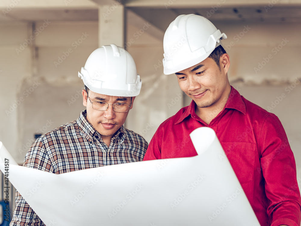 Group of engineer/architect/worker man and woman discussing about building plan for construction at job site, working on desk/table with drawing/blueprint/business plan