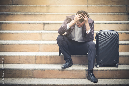 Upset young caucasian businessman tired from work sitting at stairs, unemployment, fired from job, disappointed, loss and feeling down concept © Nattakorn