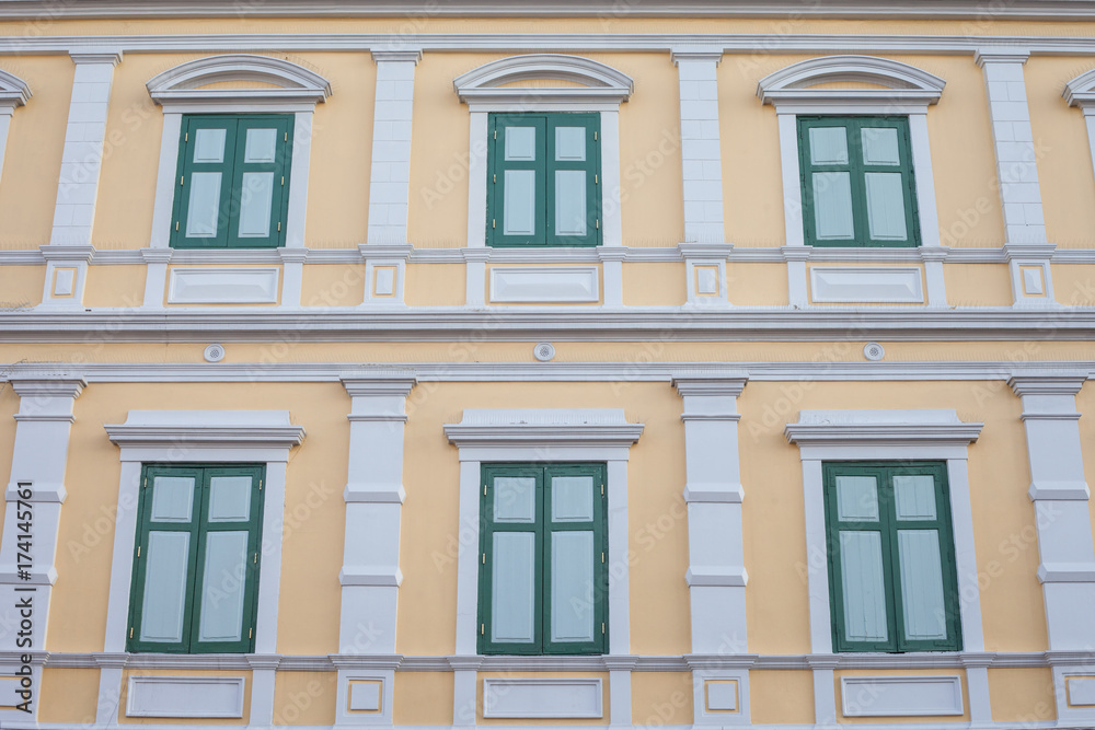 Green Windows on Yellow Vintage wall Pattern and wallpaper has architecture in Bangkok Thailand.