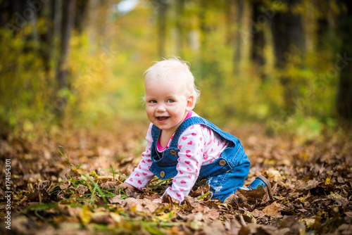 happy baby girl laughing and playing in the autumn on the forest