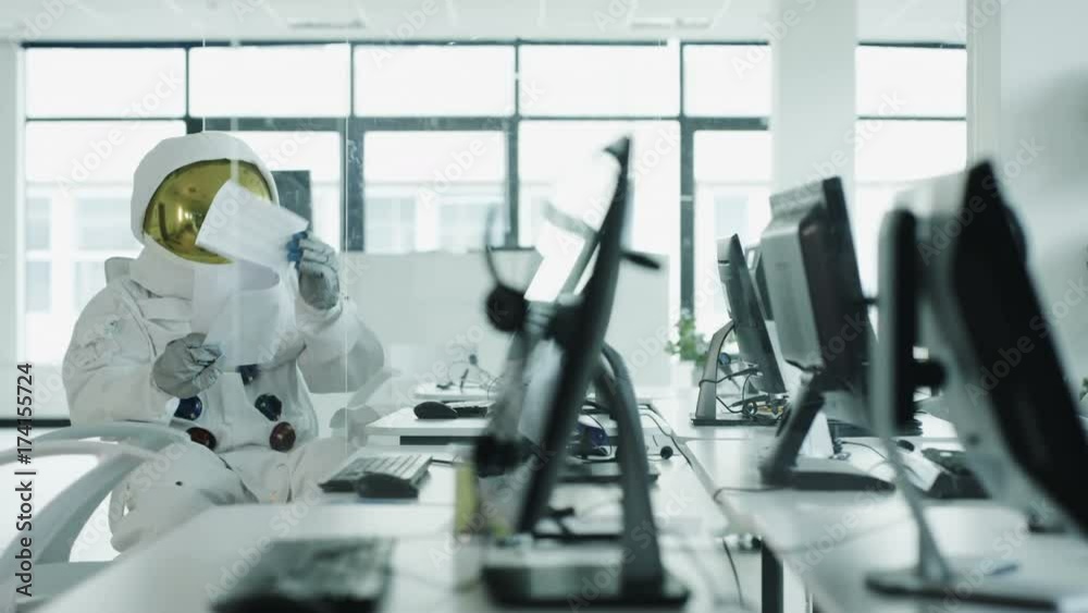  Astronaut sitting at desk in room full of computers using touch screen