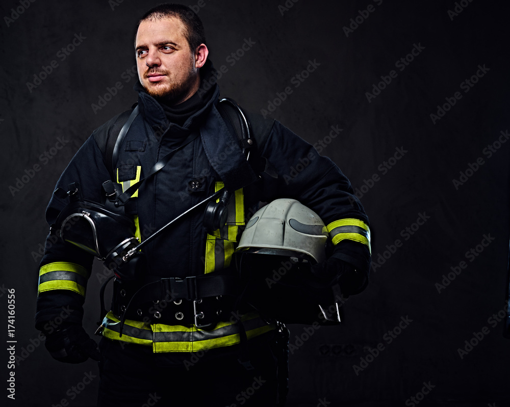 Fototapeta premium Firefighter dressed in uniform holds safety helmet.