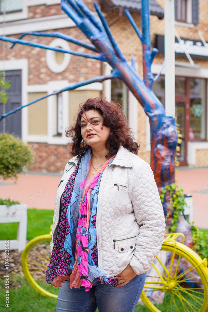 American nice and simple plus size tourist woman wear in jacket, scarf and  jeans walk on European streets and shops Stock Photo | Adobe Stock