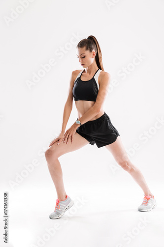 Full length portrait of a fitness woman doing stretching exercises