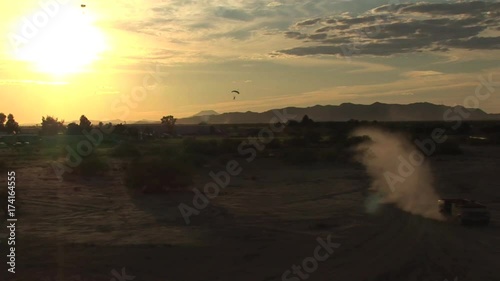 Several Skydivers Landing In The Distance With The Sunset In the Background