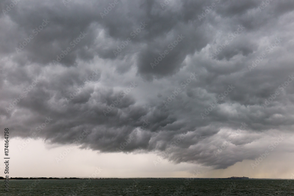 Some spectacular and menacing clouds over a lake, with a distant island in the background Some spectacular and menacing clouds over a lake, with a distant island in the background