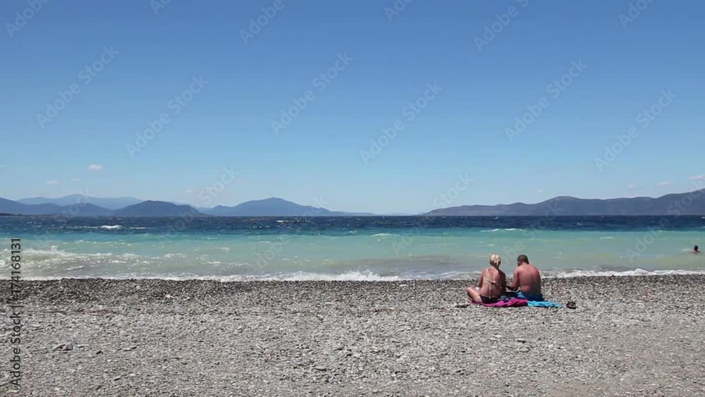 Two people, tourists are laying down to sunbathe on sandy coastline. Two people, tourists are laying down to sunbathe on sandy coastline.