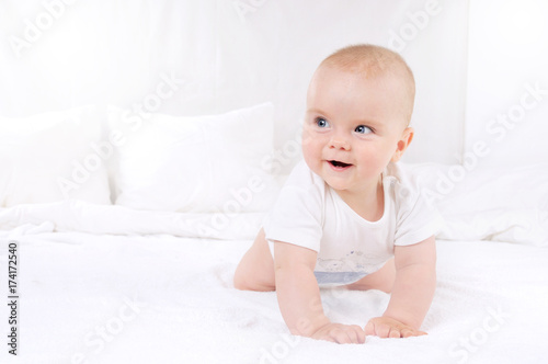 Adorable baby boy in white sunny bedroom