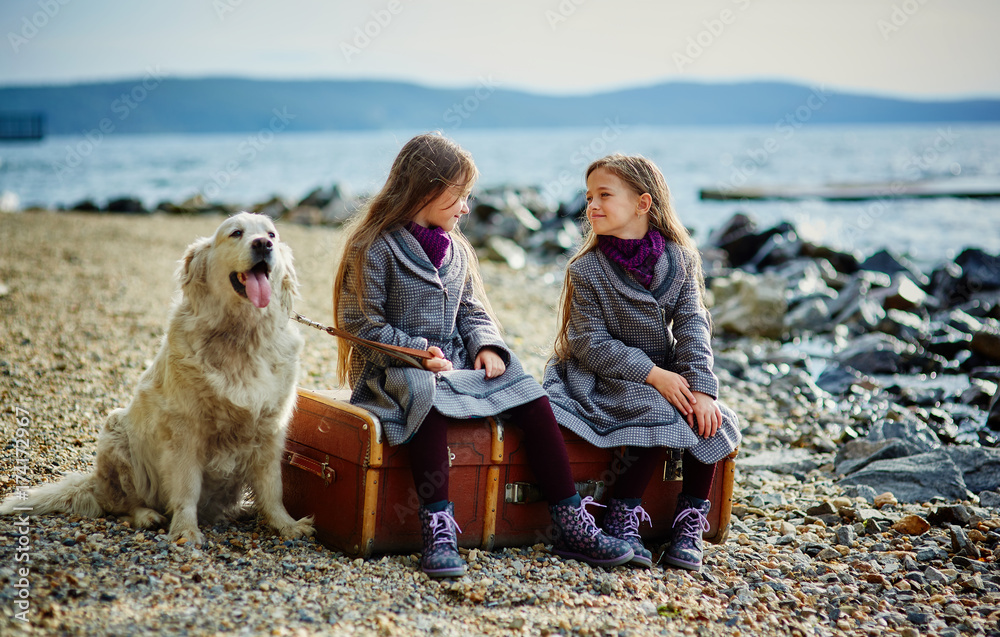 Two little twin sisters on a walk with dog on the beach. Two little twin sisters on a walk with dog on the beach.
