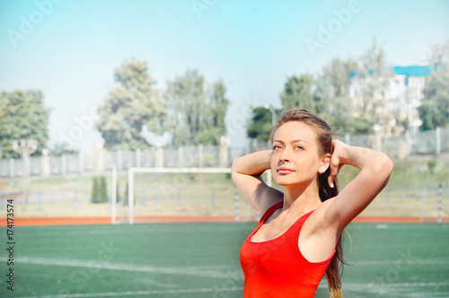 Portrait of smiling active woman standing with hands behind head © Nastassia Yakushevic