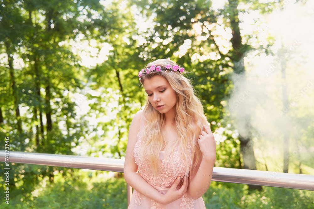 Naklejka premium Portrait of a beautiful bride blond girl in pink lace dress ,hair decoration, handmade. Tenderness. The setting sun highlights the clouds of smoke near the face