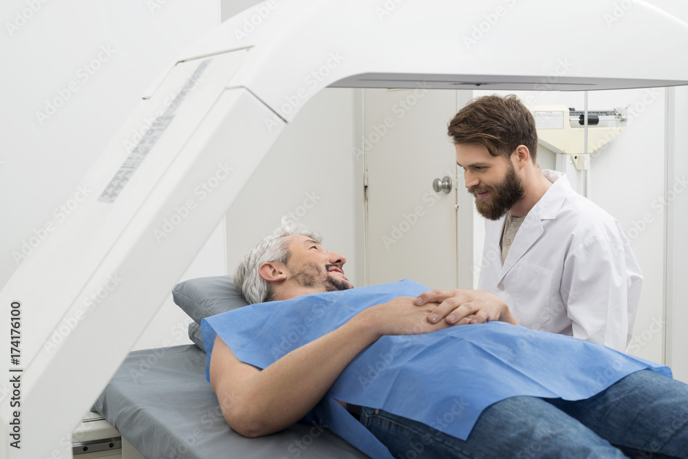 Obraz premium Medical Professional Preparing Man For X-ray Scan In Hospital