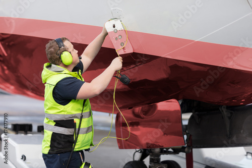 Ground Staff Member Adjusting Communication Cable On Outer Airpl photo